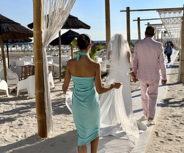 Beach wedding ceremony with bride, groom, and guests.