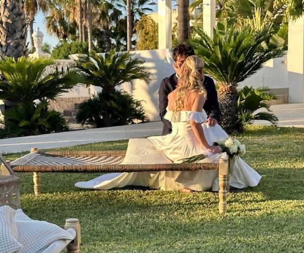 Beach wedding ceremony with decorated chairs and ocean view.