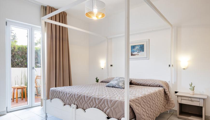 Chambre lumineuse avec lit à baldaquin et balcon.