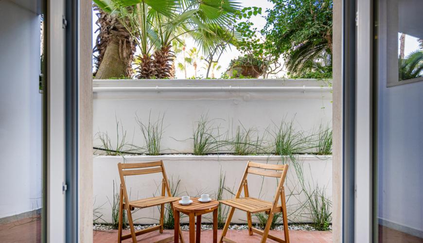 Deux chaises et une table dans un jardin avec des palmiers.