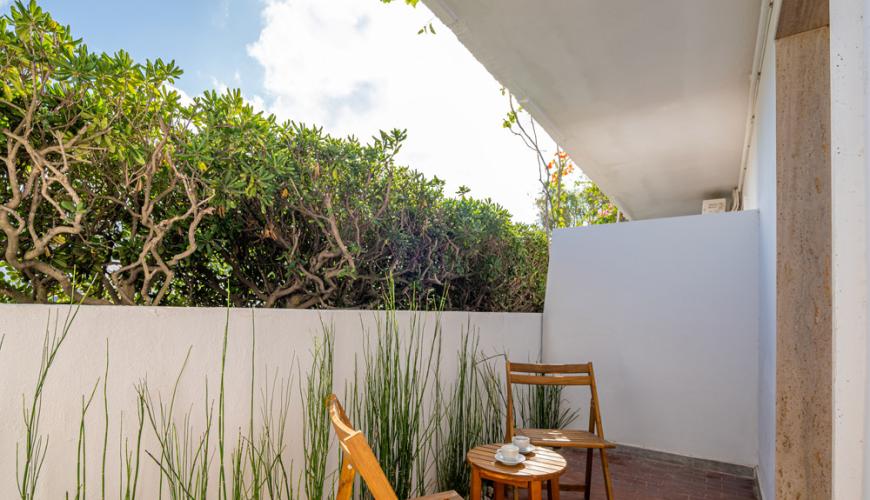 Petit balcon avec chaises en bois et plantes vertes.