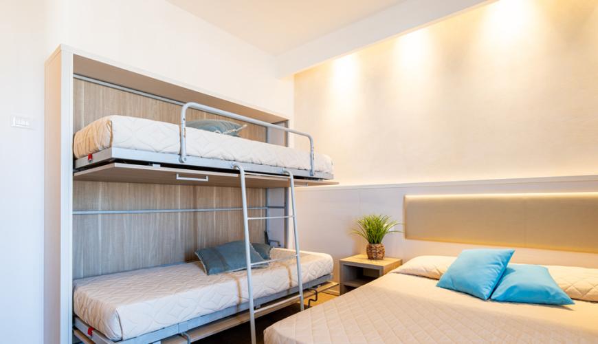 Camera con letto matrimoniale e letti a castello moderni.