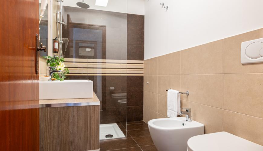 Bagno moderno con doccia, lavabo e bidet, piastrelle beige e marroni.