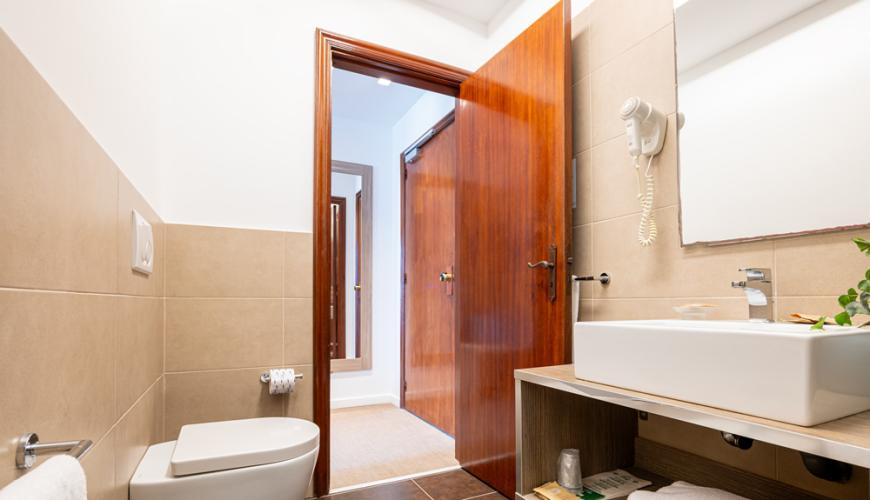 Bagno moderno con lavabo, bidet e asciugacapelli a parete.